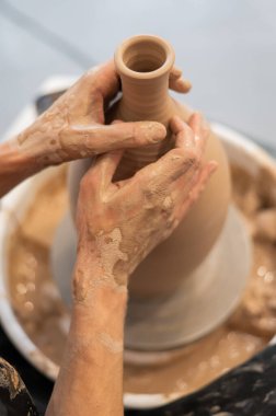 Çömlekçi elleriyle çömlekçi çarkında seramik vazo yaparken.