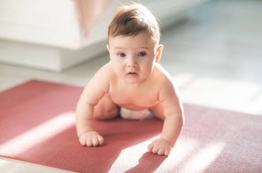 Yerde dört ayak üstünde duran sevimli küçük çocuk.