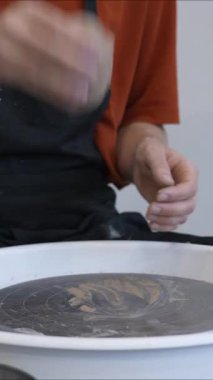 Çömlekçi, çömlekçi çarkında kullanmadan önce kil yoğurur. Dikey video