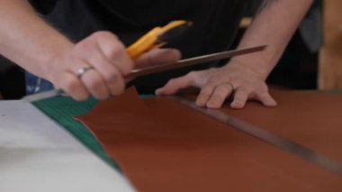 Deri işçisi atölyede deri kesip ölçüyor.