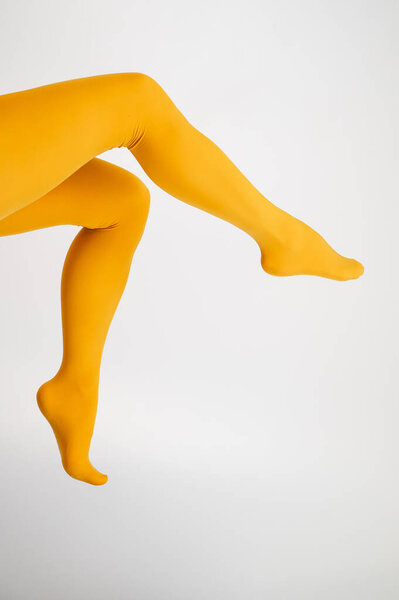 Female legs in ocher tights on a white background. Vertical photo