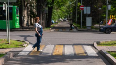 Kör hamile kadın yaya geçidinde bastonuyla karşıdan karşıya geçiyor.