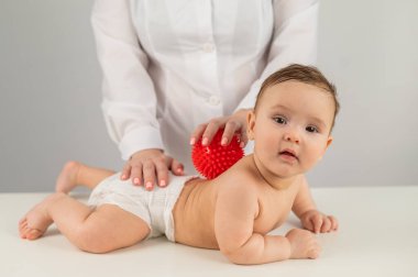 Doktor bir çocuğa top kullanarak sırt masajı yapar.