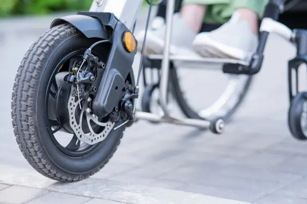 stock image A faceless woman in a wheelchair with an assistive device for manual control. Electric handbike