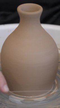 Bir çömlekçi çömlekçi çarkından bitmiş bir vazoyu keser.