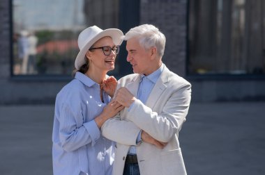 Aşık yaşlı bir çift şehirde yürür. Beyaz saçlı şık bir erkek ve kadının portresi.