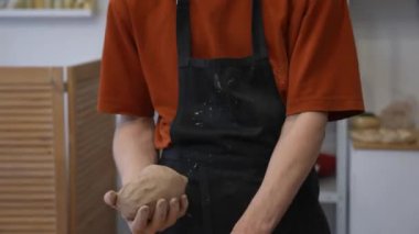 A potter kneads clay before using it in the workshop. Close-up of a mans hands