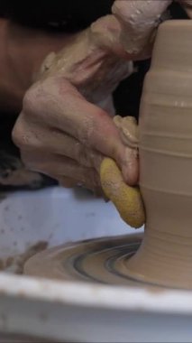 Çömlekçi ellerinin çömlekçi çarkında seramik sürahi yapmasının yakın çekimi. Dikey video