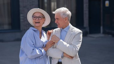 Aşık yaşlı bir çift şehirde yürür. Beyaz saçlı şık bir erkek ve kadının portresi.