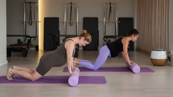 stock image Two pregnant women do a plank with bolsters. Yoga for pregnant women