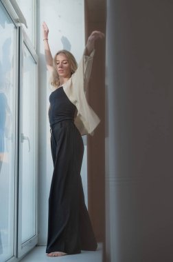 Kafkasyalı kadın pencere kenarında modern dans ediyor. Dikey fotoğraf