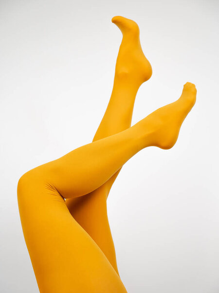 Female legs in ocher tights on a white background. Vertical photo