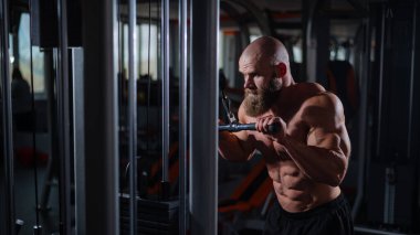 Kel Kafkas vücut geliştirici kabloyla ağır triseps egzersizleri yapıyor.