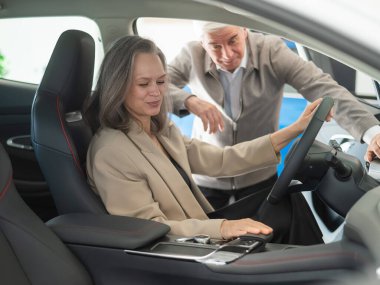 Yaşlı bir çift bir araba galerisinde yeni bir araba seçer. Olgun kadın sürüyor.