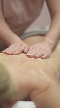 Beyaz bir kadın sırtında elle masaj yaptırıyor. Dikey video