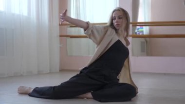 Beyaz kadın bale sınıfında yerde çağdaş dans ediyor.