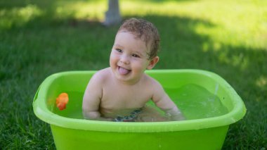 Tatlı erkek bebek yazın havuzda yıkanır.