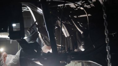 Bir otomobil tamircisi korozyon önleyici maddeyi arabanın alt gövdesine uygular.