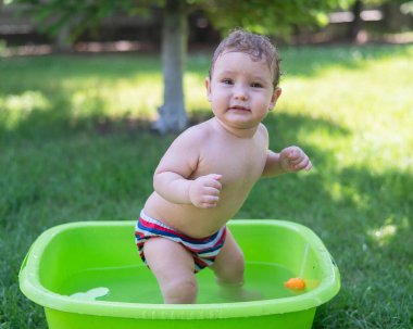 Tatlı erkek bebek yazın havuzda yıkanır.