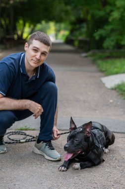 Beyaz bir adam pitbull teriyeri köpeğiyle yürüyor. Dikey fotoğraf