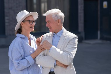 Aşık yaşlı bir çift şehirde yürür. Beyaz saçlı şık bir erkek ve kadının portresi.