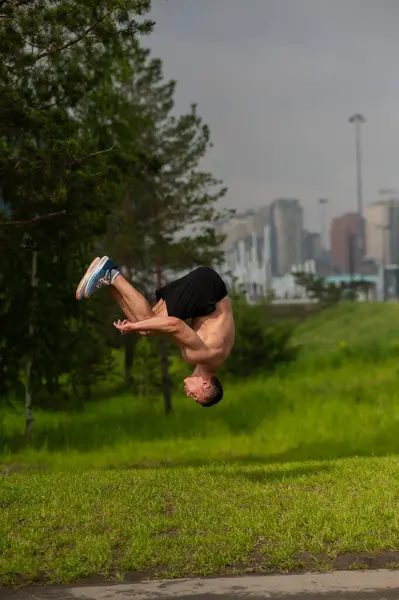 Stock image Young shirtless male athlete doing backflip on outdoors. Vertical photo