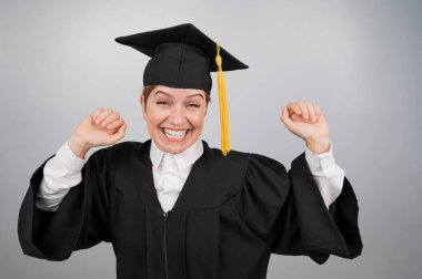 Beyaz arka planda mezuniyet elbisesiyle dans eden beyaz kadın.