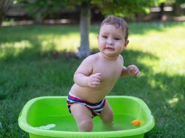 Tatlı erkek bebek yazın havuzda yıkanır.