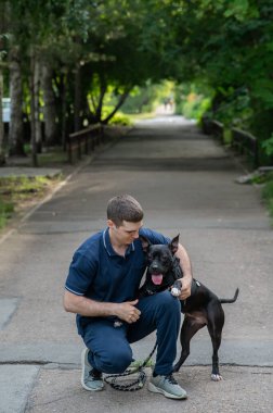 Beyaz bir adam pitbull teriyeri köpeğiyle yürüyor. Dikey fotoğraf