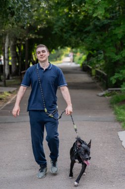 Beyaz bir adam pitbull teriyeri köpeğiyle yürüyor. Dikey fotoğraf