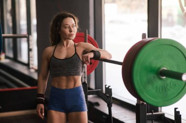 Orta yaşlı bir kadın spor salonunda ağırlık kaldırmadan önce dinleniyor.