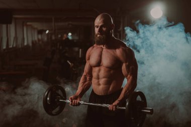 Beyaz, kel, üstsüz bir adam spor salonunda halterle egzersiz yapıyor. Ağırlıklarla bibik bukleler