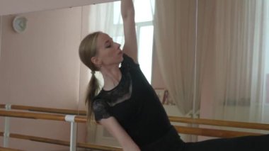 Kafkasyalı sarışın kadın sınıfta bale çalışıyor. Balerin barda prova yapıyor.