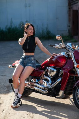 Kırmızı motosikletli şortlu esmer kadın. Dikey fotoğraf