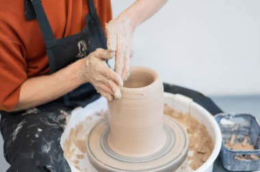 Çömlekçi elleriyle çömlekçi çarkında seramik vazo yaparken.