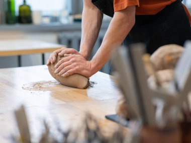 A potter kneads clay before using it in the workshop. Close-up of a mans hands