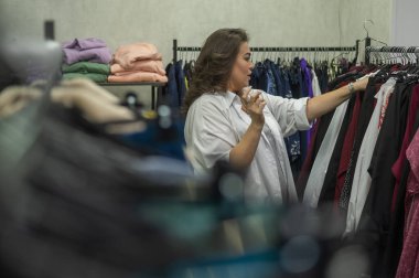 Şişman bir kadın büyük boy mağazadan kıyafet seçer.