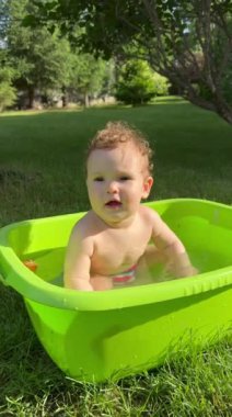 Yazın dışarıdaki havuzda şirin bebek banyosu yapıyor. Dikey video