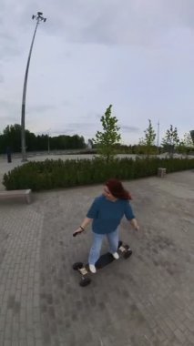 Beyaz bir kadın uzaktan kumandalı elektrikli bir uzun tahta kullanıyor. Dikey video