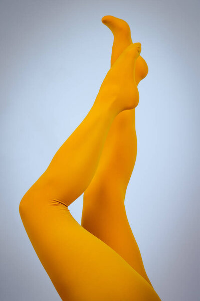 Female legs in ocher tights on a white background. Vertical photo