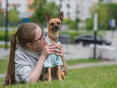 Küçük bir köpekle yürürken çimenlerde yatan beyaz bir kadın.