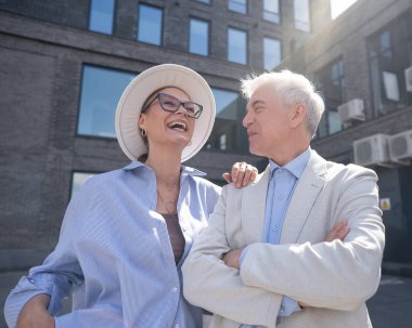 Aşık yaşlı bir çift şehirde yürür. Beyaz saçlı şık bir erkek ve kadının portresi.