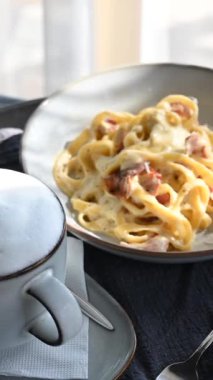 Yuvarlak masada dönen bir tabak makarna ve kahve. Dikey video