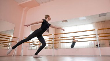 Kafkasyalı sarışın kadın sınıfta bale çalışıyor. Balerin barda prova yapıyor.