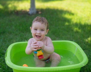 Tatlı erkek bebek yazın havuzda yıkanır.