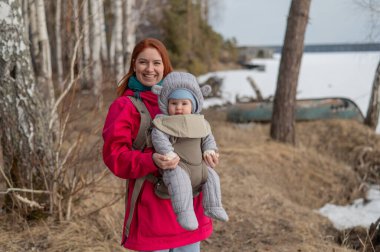 Kafkasyalı kızıl saçlı kadın kışın doğada oğluyla birlikte sırt çantasıyla dolaşıyor.