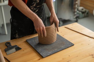 Close-up of a mans hands making a patterned cylinder out of clay clipart