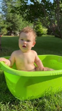 Yazın dışarıdaki havuzda şirin bebek banyosu yapıyor. Dikey video