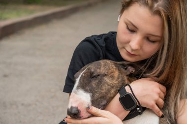 Beyaz kadın portresi açık havada köpeğine sarılıyor.