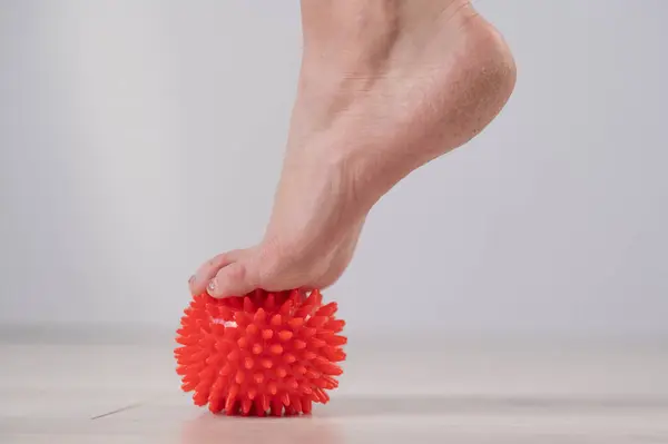 Stock image Close-up of a womans foot on a massage ball with spikes